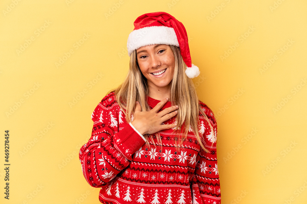 Young caucasian woman celebrating Christmas isolated on yellow background laughs out loudly keeping hand on chest. Young caucasian woman celebrating Christmas isolated on yellow background laughs out loudly keeping hand on chest.