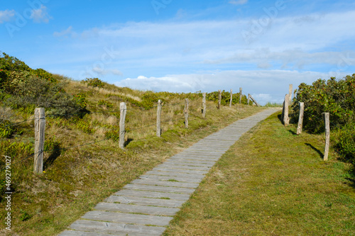 Germany, Lower Saxony, Wangerooge, Fenced boardwalk across grassy dunes photo