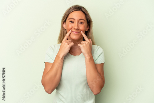 Young caucasian woman isolated on green background doubting between two options.