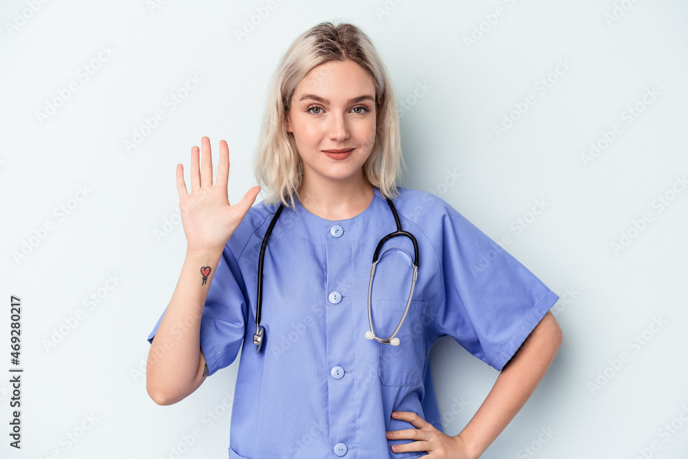 Young nurse woman isolated on blue background smiling cheerful showing number five with fingers. Young nurse woman isolated on blue background smiling cheerful showing number five with fingers.