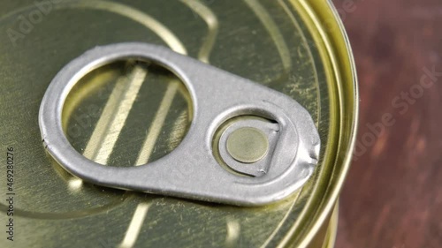 Conserved food aluminium can with pull ring on a wooden background. Unopened hermetic container. Macro. Slow rotation