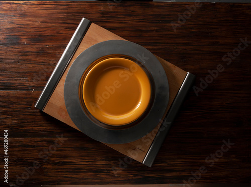 Plato  naranja y negro sobre fondo de madera, vista cenital. Orange  and black plate on wooden background, overhead view. photo