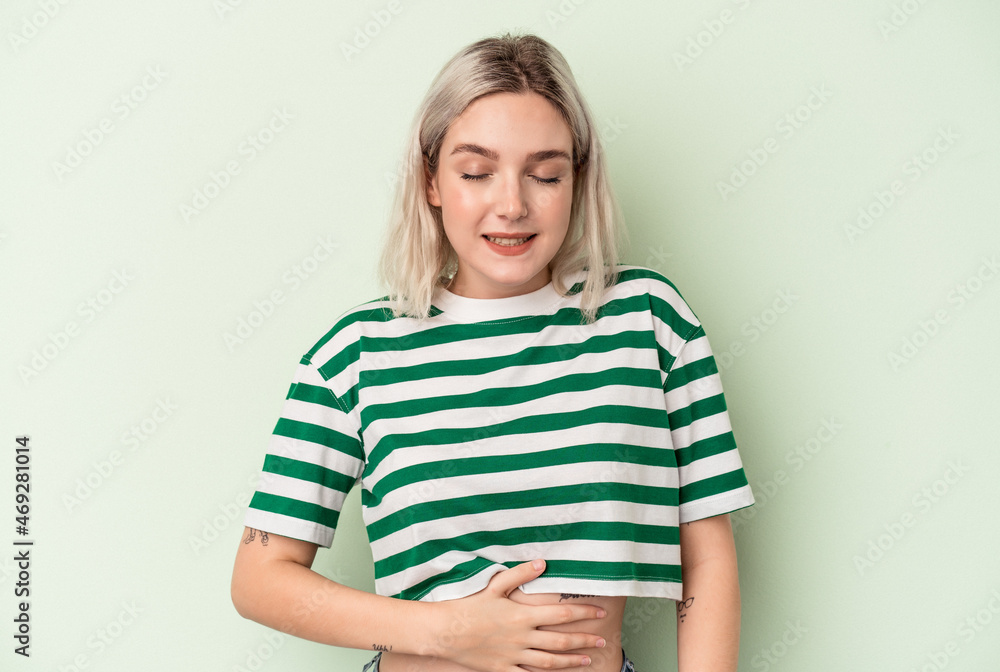 Young caucasian woman isolated on green background touches tummy, smiles gently, eating and satisfaction concept. Young caucasian woman isolated on green background touches tummy, smiles gently, eating and satisfaction concept.