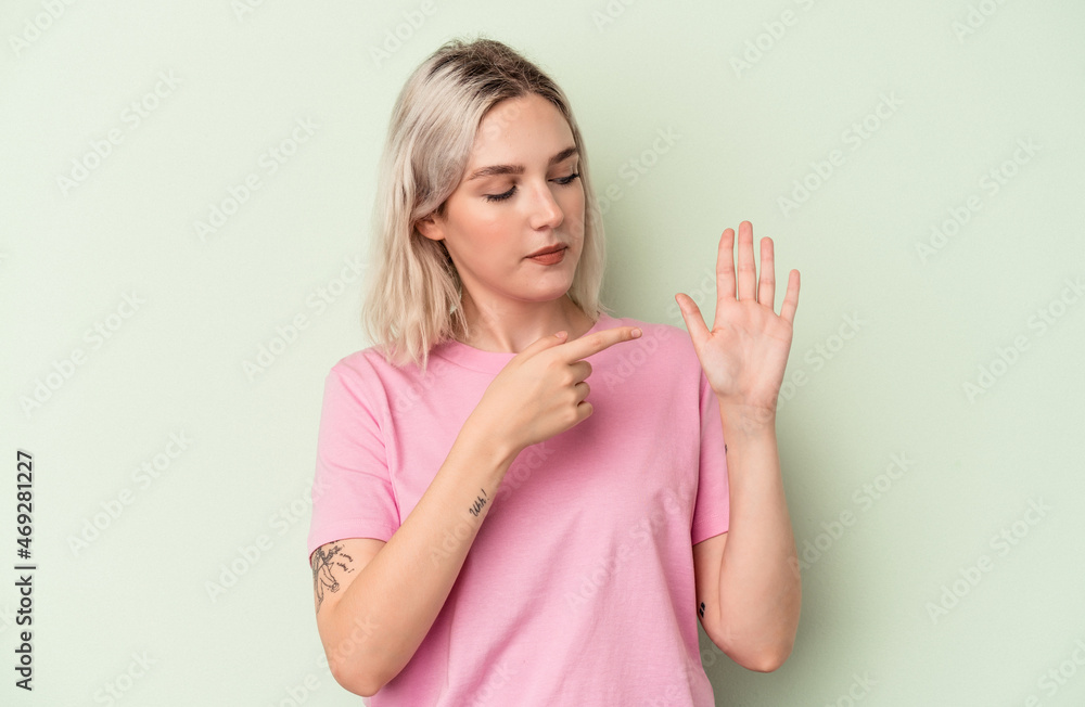 Young caucasian woman isolated on green background smiling cheerful showing number five with fingers. Young caucasian woman isolated on green background smiling cheerful showing number five with fingers.