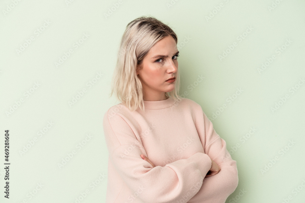 Young caucasian woman isolated on green background suspicious, uncertain, examining you. Young caucasian woman isolated on green background suspicious, uncertain, examining you.