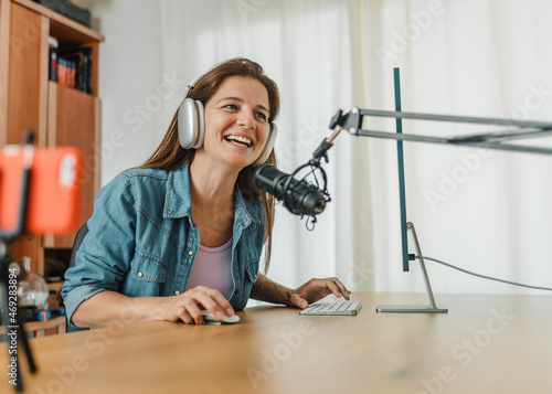 Happy woman in headphones recording podcast and using computer
