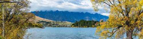 ニュージーランド　秋のクイーンズタウンのワカティプ湖の湖畔から見えるリマーカブルズ山脈とワカティプ湖と紅葉で色づいた木々 © pespiero