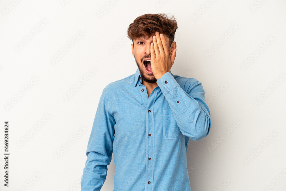 Young mixed race man isolated on grey background having fun covering half of face with palm. Young mixed race man isolated on grey background having fun covering half of face with palm.