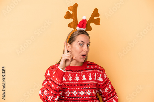 Young caucasian woman wearing a christmas reindeer hat isolated on yellow background having an idea  inspiration concept.