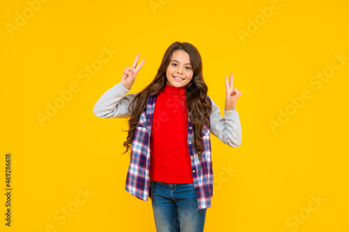 peace gesture. glad teen girl has long curly hair. back to school. female fashion model.