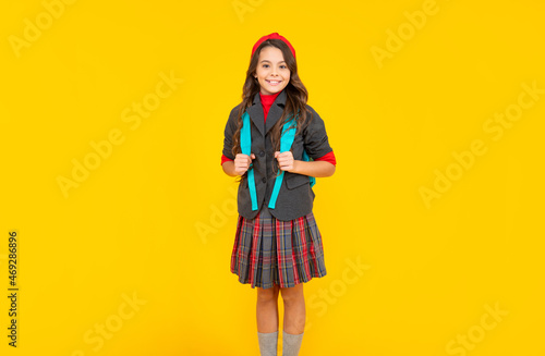 happy teen girl in uniform with school bag on yellow background, school