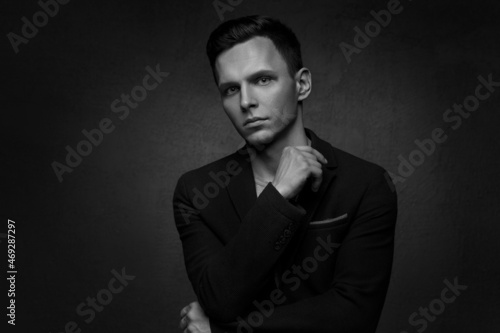 Black and white portrait of a handsome business man in a suit against a dark background.