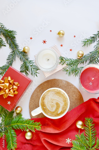 Cup of coffee with candles, gift box, fir tree branches, Christmas decorations on the white background. Merry Christmas mood. Cozy, comfort new year atmosphere. New year morning coffee. Place for text