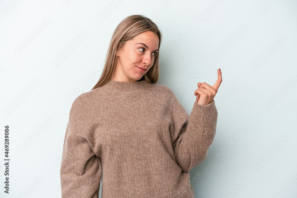 Young caucasian woman isolated on blue background pointing with finger at you as if inviting come closer. Young caucasian woman isolated on blue background pointing with finger at you as if inviting come closer.