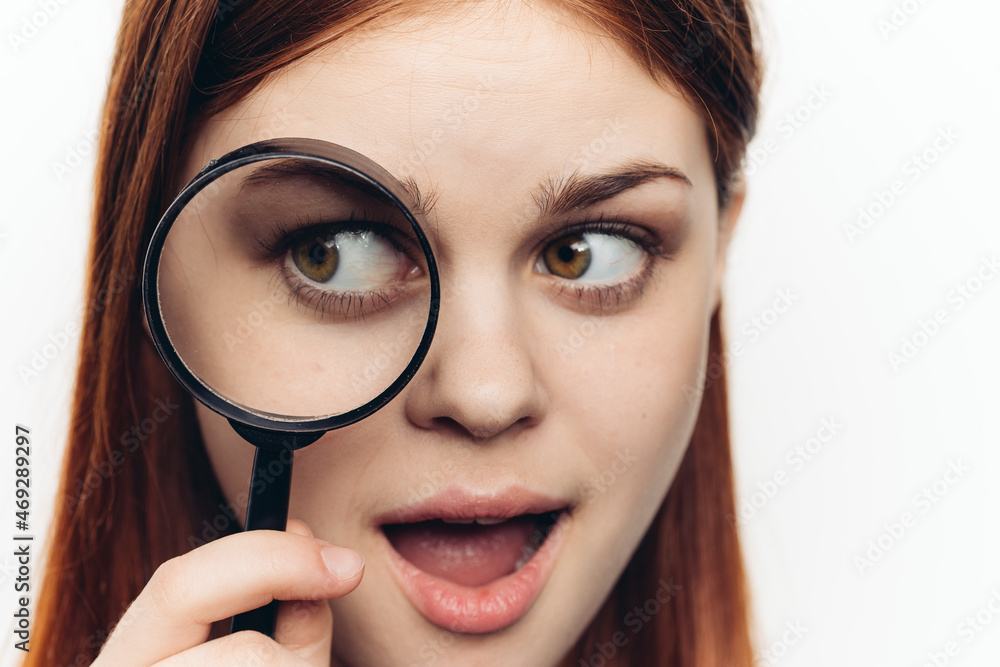 pretty woman grimacing with magnifying glass near face close-up pretty woman grimacing with magnifying glass near face close-up