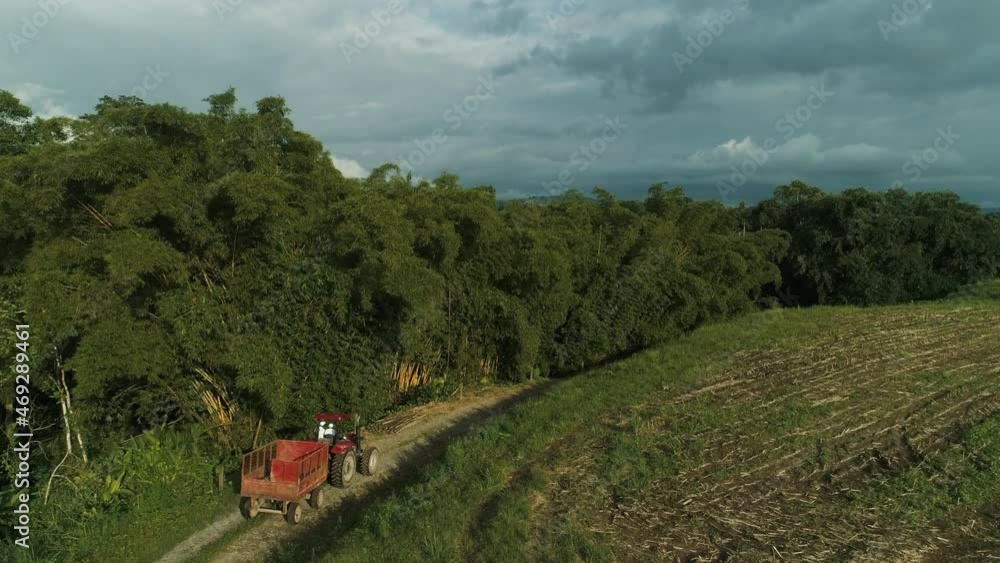 Red tractor going down the road, green felds and trees Red tractor going down the road, green felds and trees