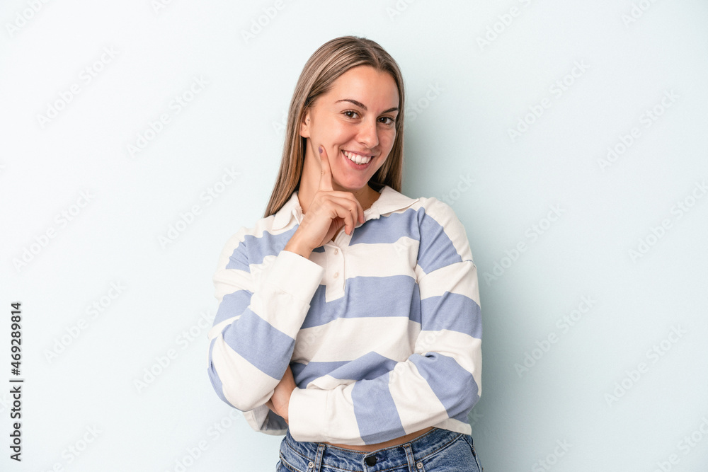 Young caucasian woman isolated on blue background smiling happy and confident, touching chin with hand. Young caucasian woman isolated on blue background smiling happy and confident, touching chin with hand.