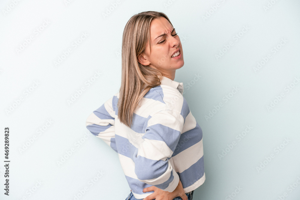 Young caucasian woman isolated on blue background suffering a back pain. Young caucasian woman isolated on blue background suffering a back pain.