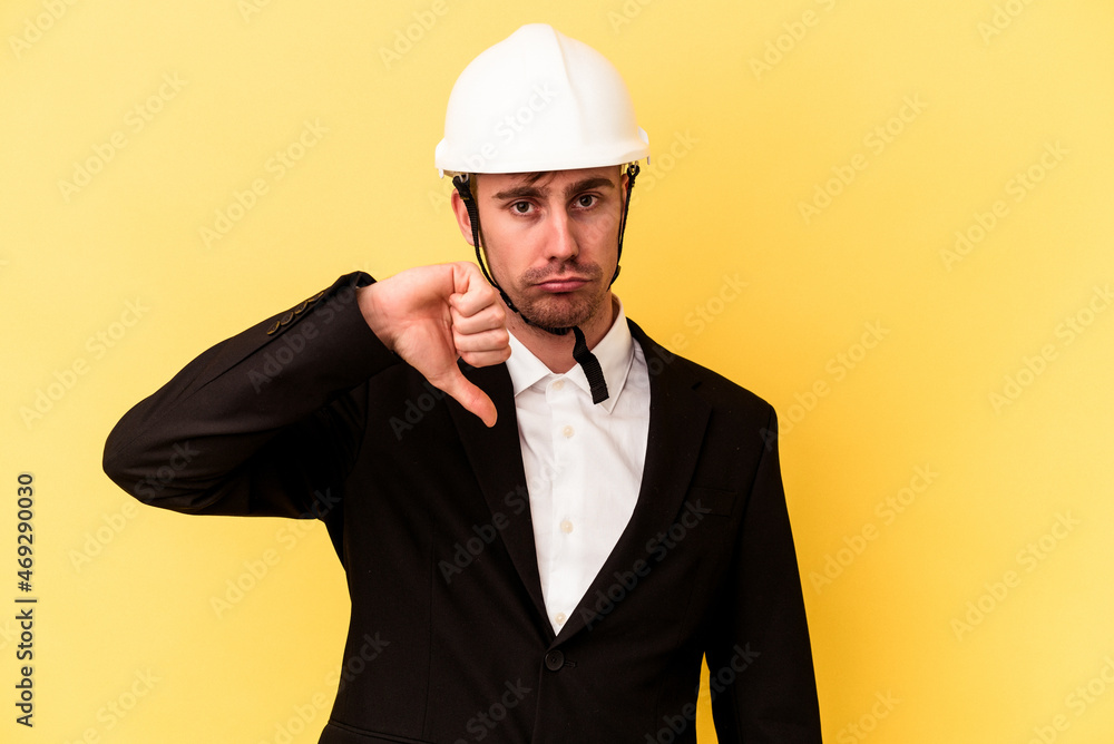 Young architect caucasian man isolated on yellow background showing a dislike gesture, thumbs down. Disagreement concept.