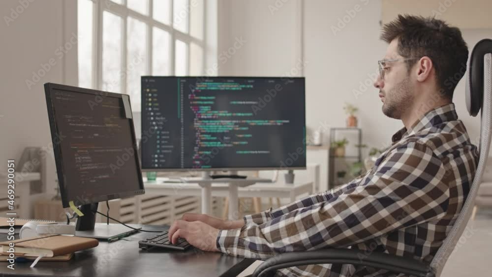 Side-view stab shot of professional system administrator or software developer writing program codes on pc computer working alone in modern office Side-view stab shot of professional system administrator or software developer writing program codes on pc computer working alone in modern office