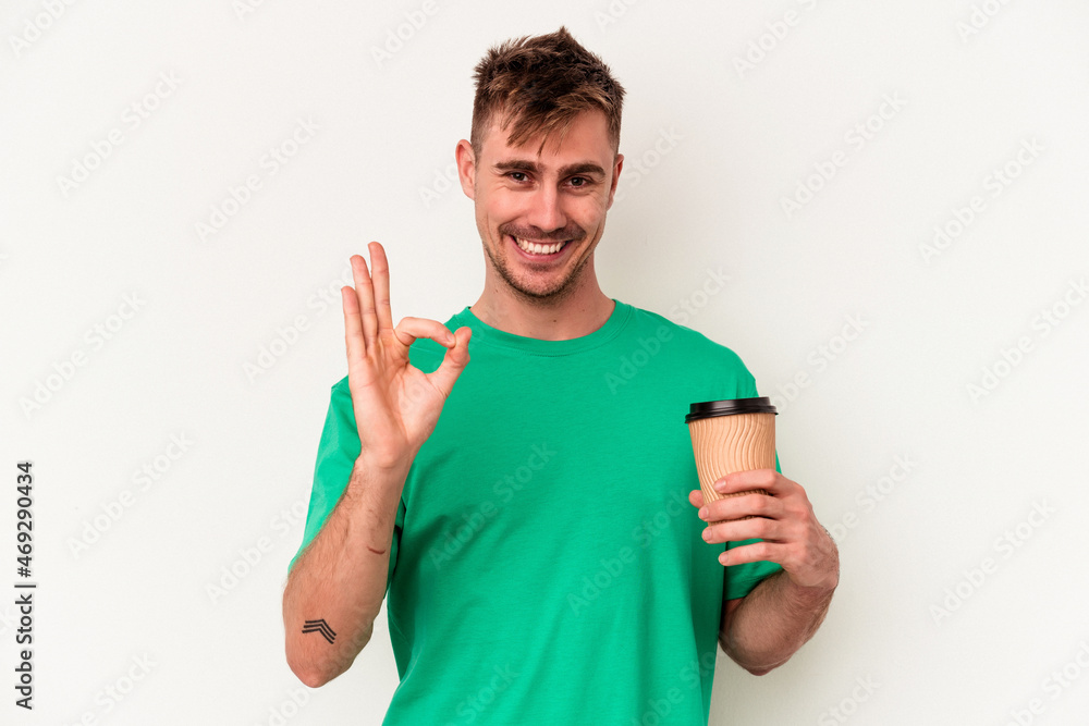 Young caucasian man holding a take away coffee isolated on white background cheerful and confident showing ok gesture. Young caucasian man holding a take away coffee isolated on white background cheerful and confident showing ok gesture.