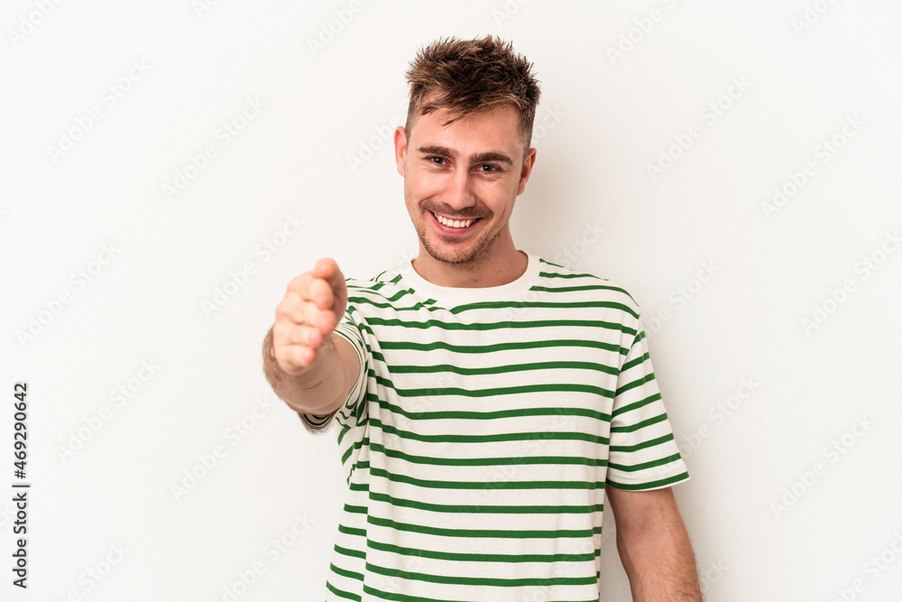 Young caucasian man isolated on white background stretching hand at camera in greeting gesture. Young caucasian man isolated on white background stretching hand at camera in greeting gesture.
