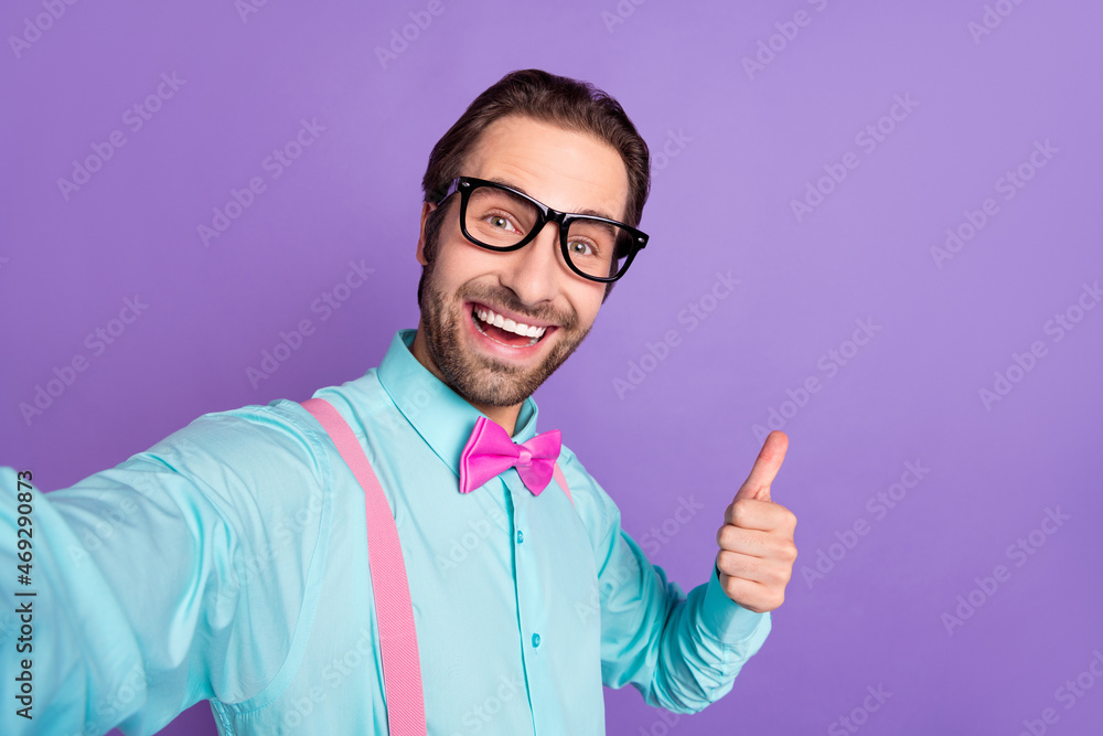 Photo of millennial brunet groomed guy show thumb up do selfie wear tie suspenders blue shirt eyewear isolated on purple background Photo of millennial brunet groomed guy show thumb up do selfie wear tie suspenders blue shirt eyewear isolated on purple background