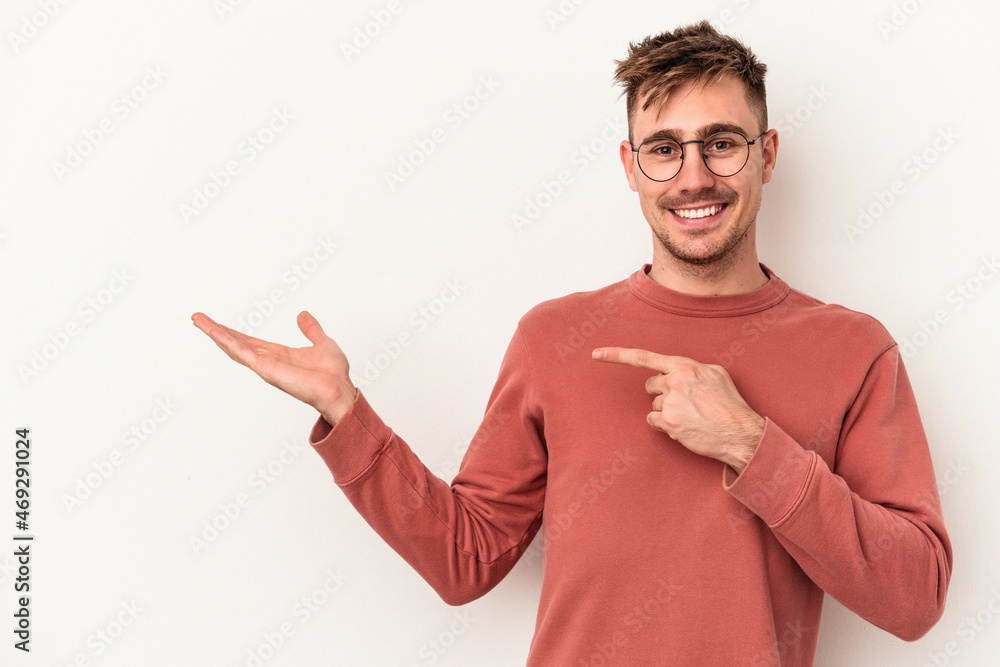 Young caucasian man isolated on white background excited holding a copy space on palm. Young caucasian man isolated on white background excited holding a copy space on palm.