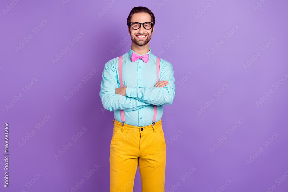 Photo of cool young brunet man crossed hands wear tie suspenders blue shirt spectacles isolated on violet color background Photo of cool young brunet man crossed hands wear tie suspenders blue shirt spectacles isolated on violet color background