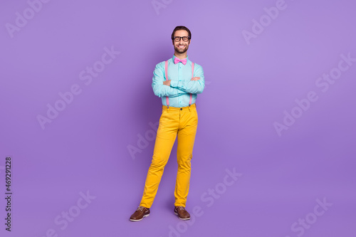 Full size photo of nice millennial hipster brunet man crossed arms wear tie suspenders shirt spectacles trousers sneakers isolated on violet background