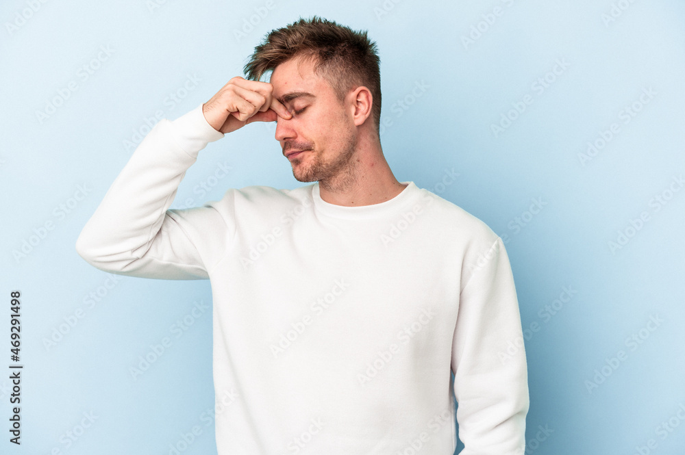 Young caucasian man isolated on blue background having a head ache, touching front of the face. Young caucasian man isolated on blue background having a head ache, touching front of the face.
