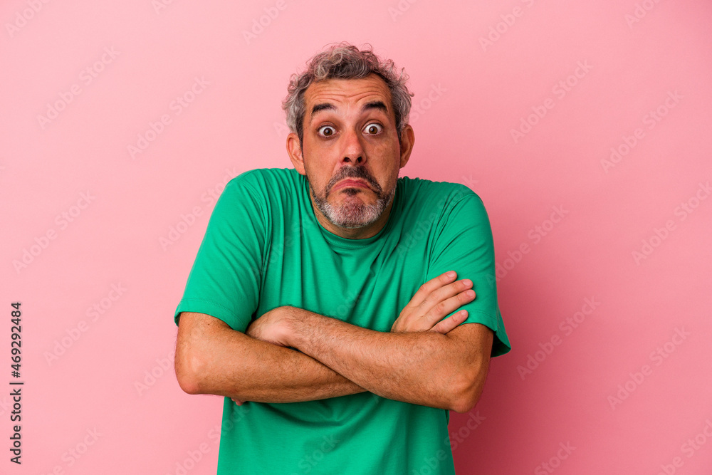 Middle age caucasian man isolated on pink background shrugs shoulders and open eyes confused. Middle age caucasian man isolated on pink background shrugs shoulders and open eyes confused.