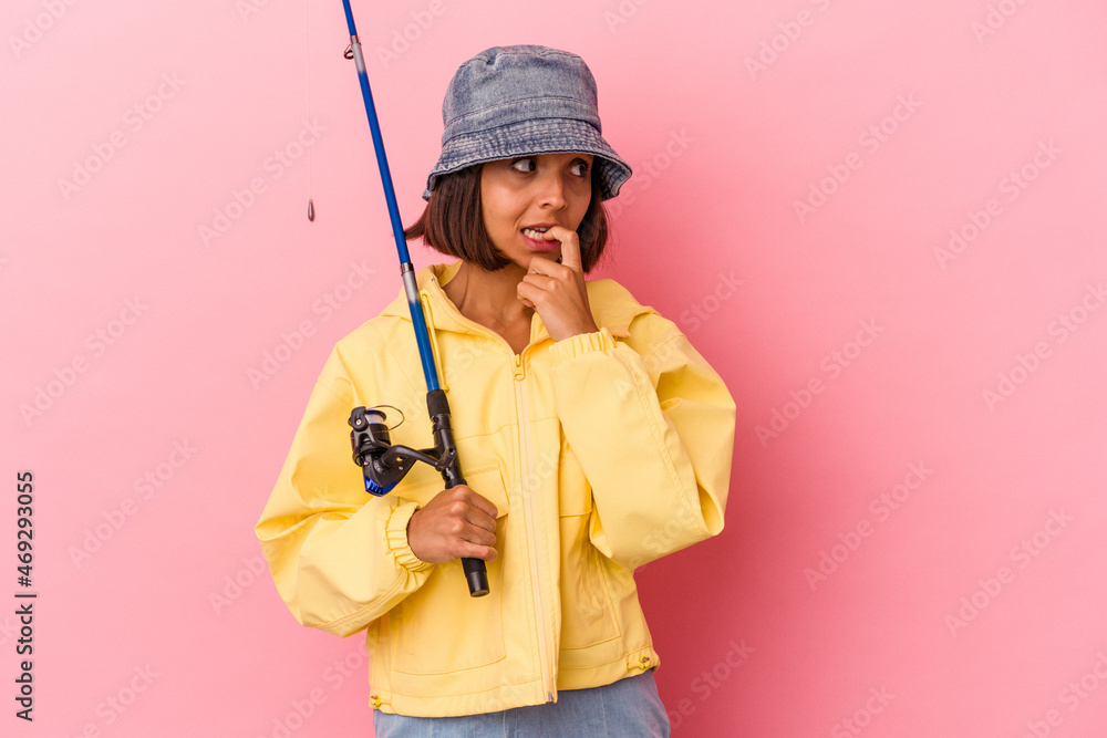 Young mixed race woman practicing fishing isolated on pink background relaxed thinking about something looking at a copy space. Young mixed race woman practicing fishing isolated on pink background relaxed thinking about something looking at a copy space.