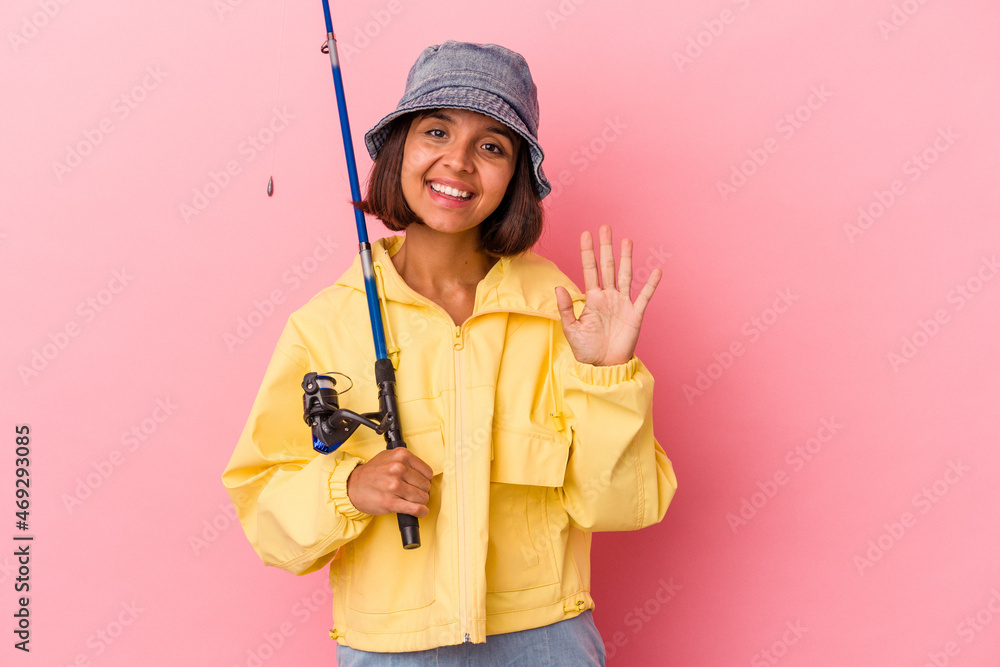 Young mixed race woman practicing fishing isolated on pink background smiling cheerful showing number five with fingers. Young mixed race woman practicing fishing isolated on pink background smiling cheerful showing number five with fingers.