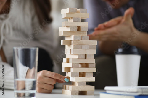 Womans hand pull one of wooden blocks from high build tower