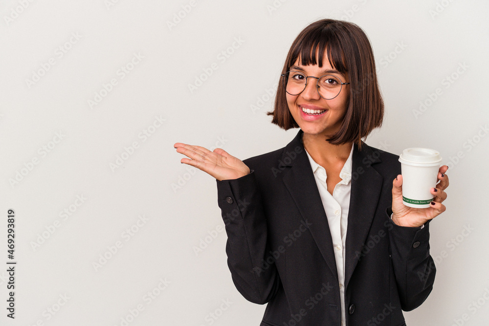 Young mixed race business woman holding a coffee isolated on white background showing a copy space on a palm and holding another hand on waist. Young mixed race business woman holding a coffee isolated on white background showing a copy space on a palm and holding another hand on waist.