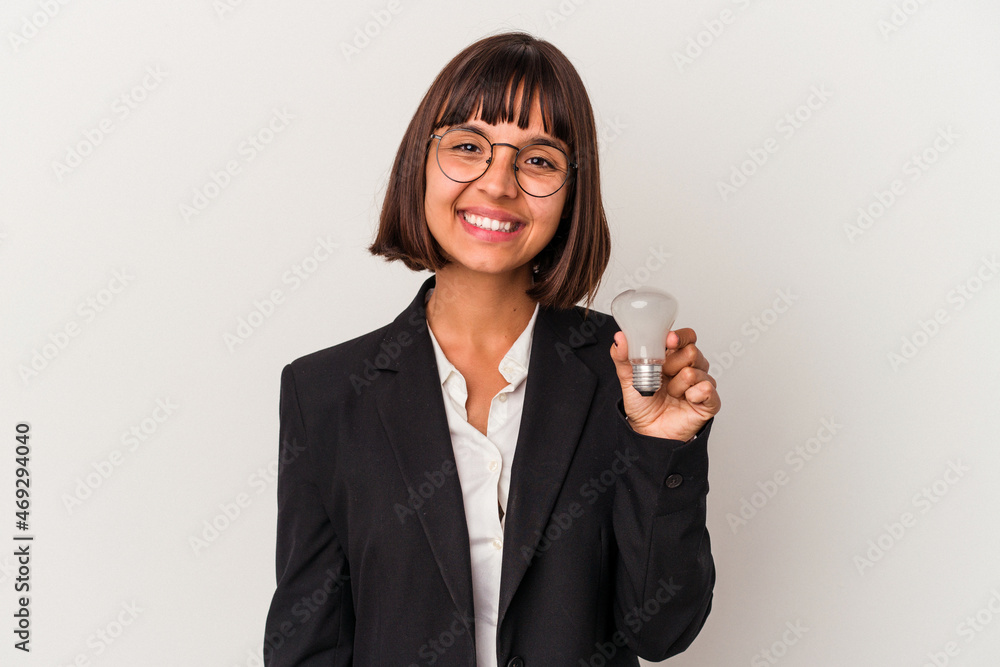 Young mixed race business woman holding a light bulb isolated on white background happy, smiling and cheerful. Young mixed race business woman holding a light bulb isolated on white background happy, smiling and cheerful.