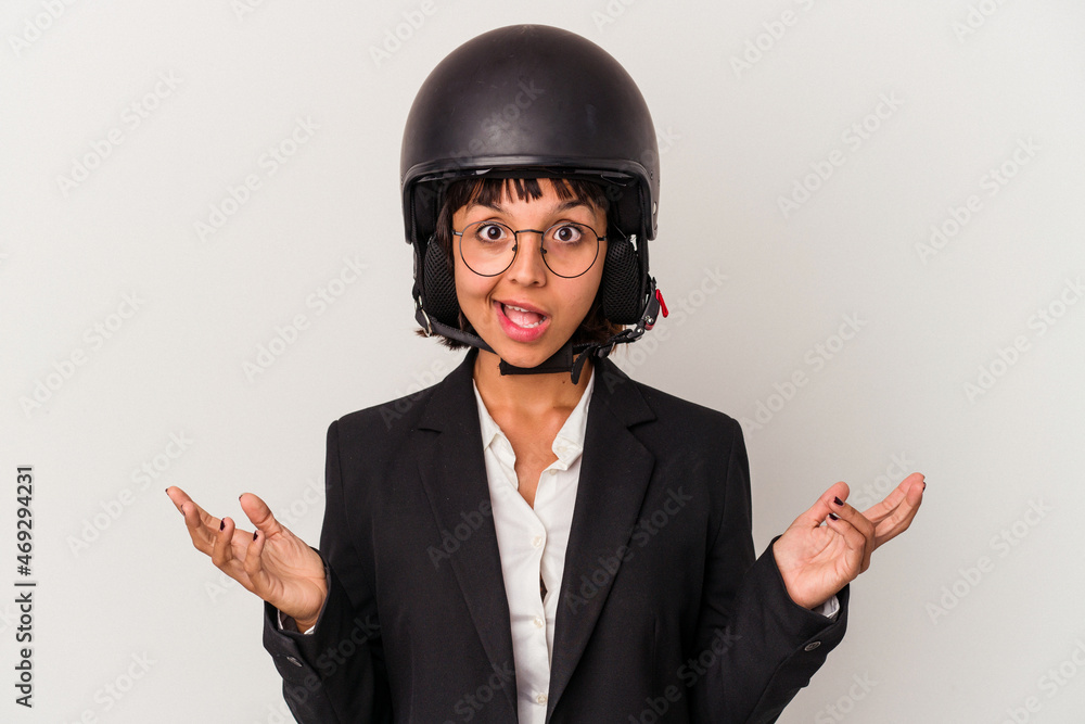 Young mixed race business woman wearing a motorbike helmet isolated surprised and shocked. Young mixed race business woman wearing a motorbike helmet isolated surprised and shocked.