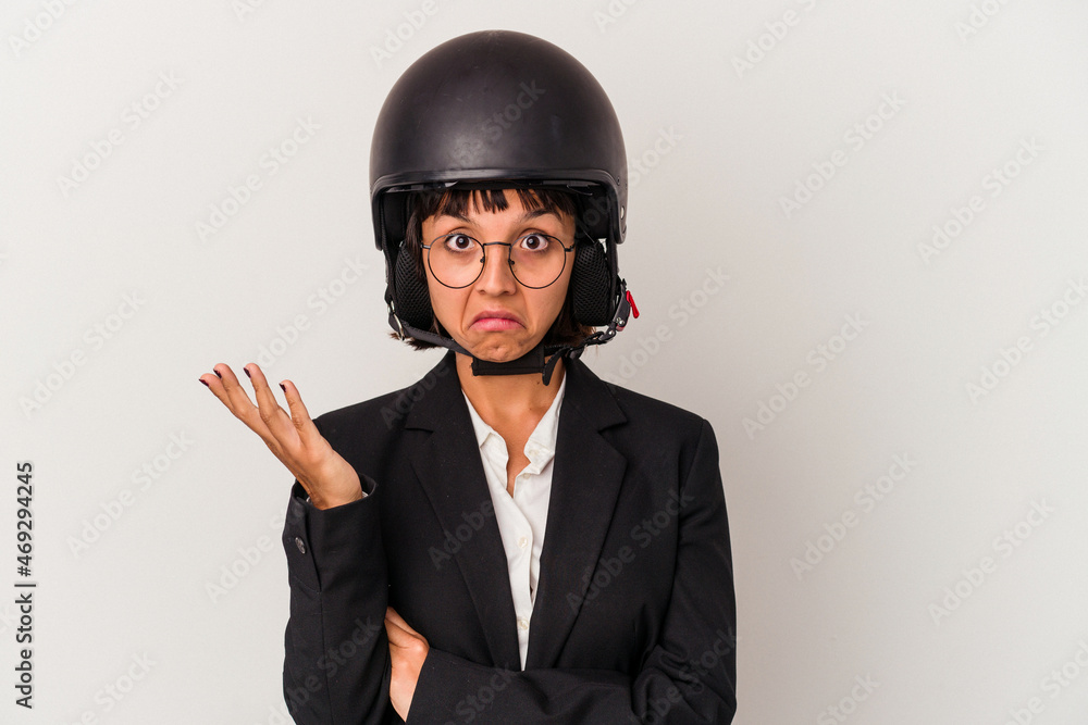Young mixed race business woman wearing a motorbike helmet isolated shrugs shoulders and open eyes confused. Young mixed race business woman wearing a motorbike helmet isolated shrugs shoulders and open eyes confused.