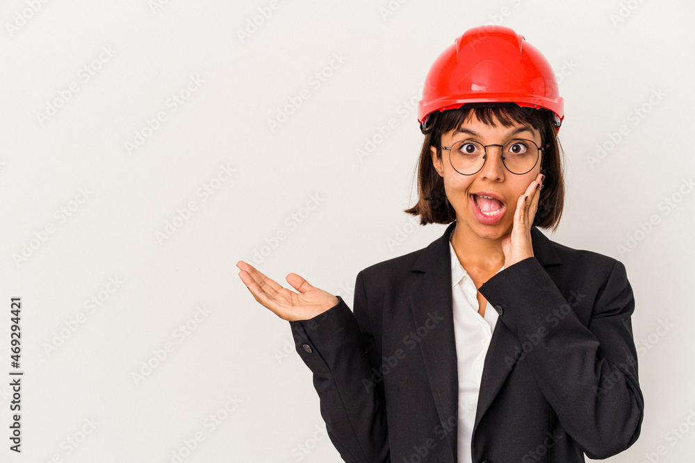 Young architect woman with red helmet isolated on white background holds copy space on a palm, keep hand over cheek. Amazed and delighted. Young architect woman with red helmet isolated on white background holds copy space on a palm, keep hand over cheek. Amazed and delighted.