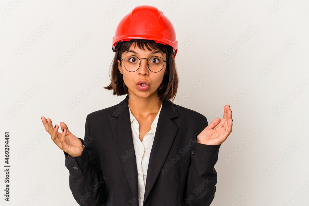 Young architect woman with red helmet isolated on white background surprised and shocked.