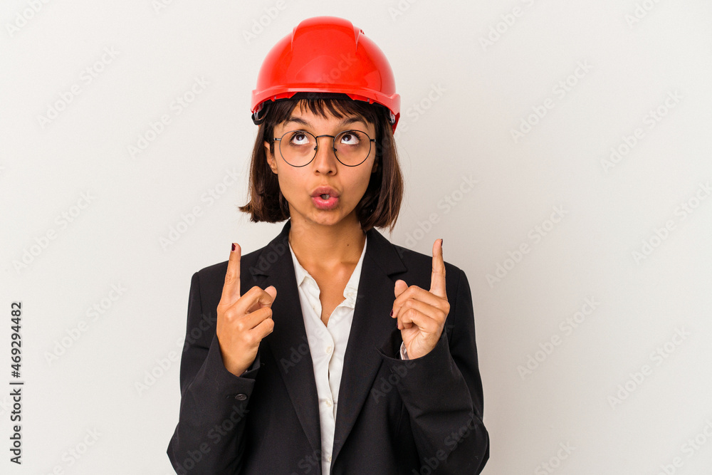 Young architect woman with red helmet isolated on white background pointing upside with opened mouth. Young architect woman with red helmet isolated on white background pointing upside with opened mouth.