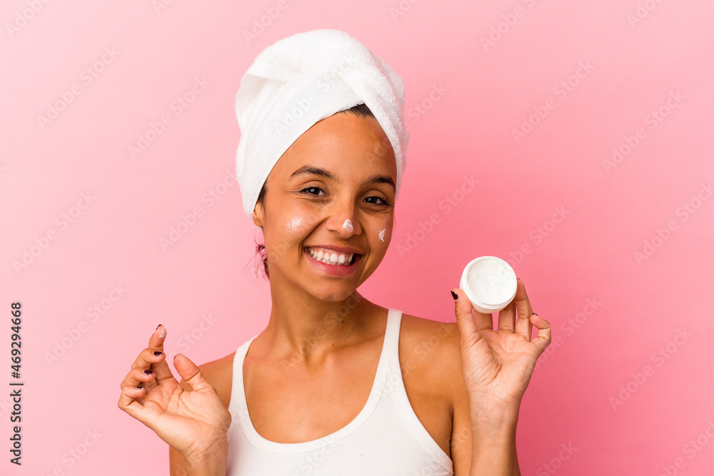 Young mixed race woman applying cream to her face isolated Young mixed race woman applying cream to her face isolated