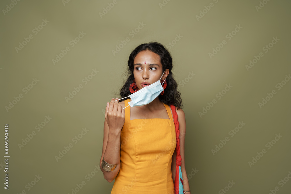 Young south asian woman wearing dress posing with face mask Young south asian woman wearing dress posing with face mask