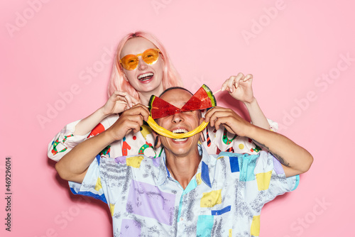 Young couple in multicolored shirts making fun with candies
