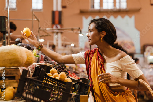 Young indian woman wearing sari making purchases in eastern market