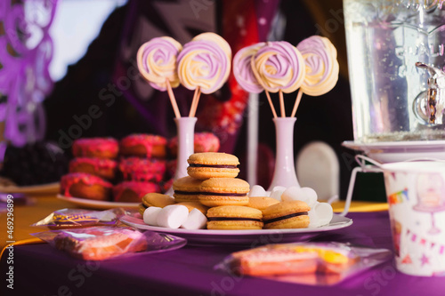 Close-up of a bright purple table decoration for a children s birthday. Party sweets donuts  macaroons  marshmallows