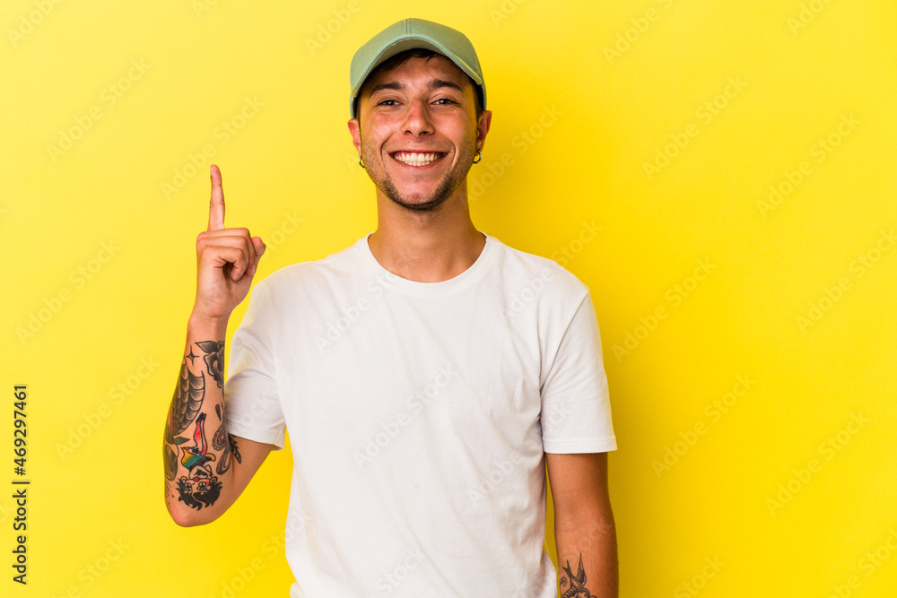 Young caucasian man with tattoos isolated on yellow background showing number one with finger. Young caucasian man with tattoos isolated on yellow background showing number one with finger.