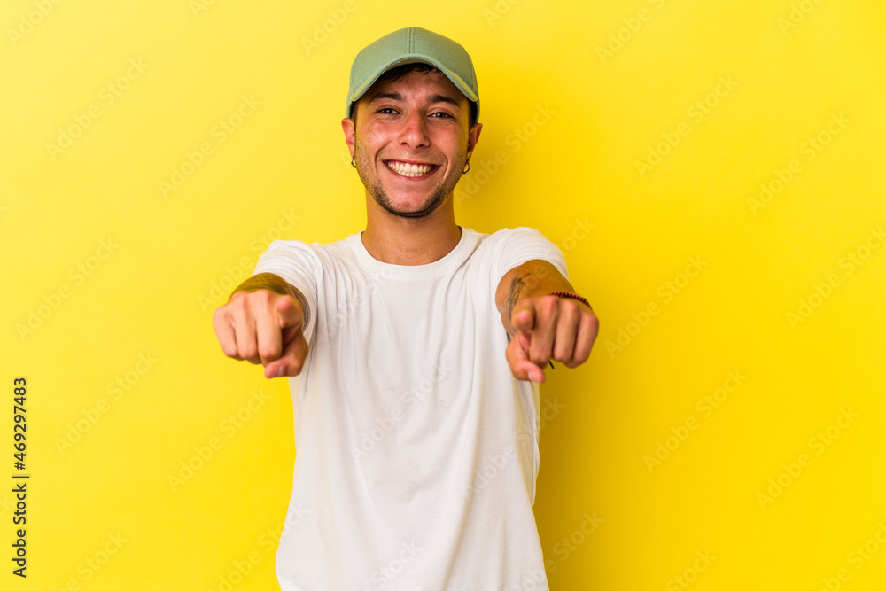 Young caucasian man with tattoos isolated on yellow background  cheerful smiles pointing to front.