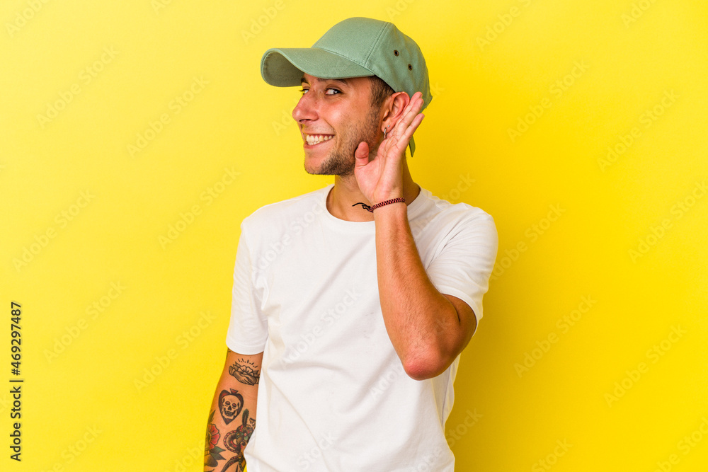 Young caucasian man with tattoos isolated on yellow background trying to listening a gossip. Young caucasian man with tattoos isolated on yellow background trying to listening a gossip.